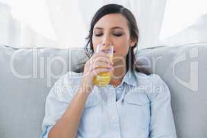 Cheerful brunette drinking orange juice