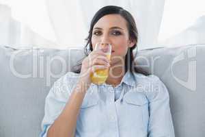 Happy brunette drinking orange juice
