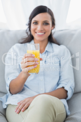 Cheerful brunette offering orange juice to camera