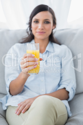 Peaceful brunette offering orange juice to camera