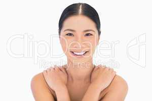 Smiling natural dark haired model posing hands on shoulders