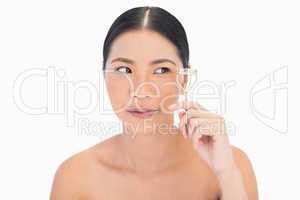Natural dark haired woman with eyelash curler