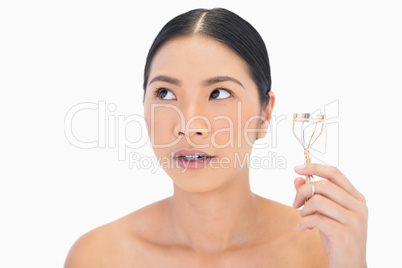 Thoughtful natural model with eyelash curler