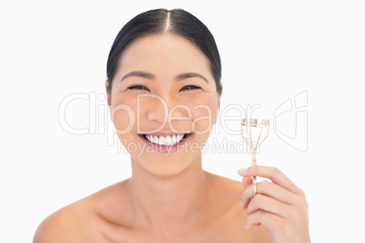 Smiling natural model holding eyelash curler
