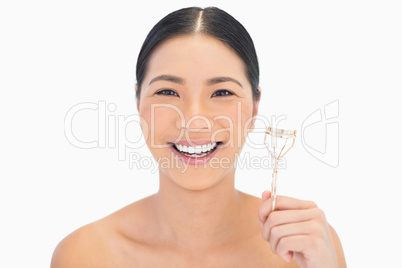 Cheerful natural model holding eyelash curler
