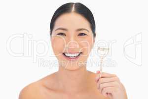 Cheerful natural model holding eyelash curler