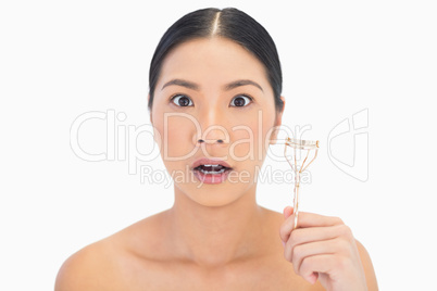 Surprised natural model holding eyelash curler