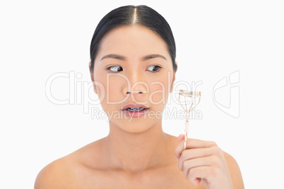 Apprehensive natural model holding eyelash curler