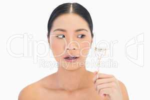 Apprehensive natural model holding eyelash curler