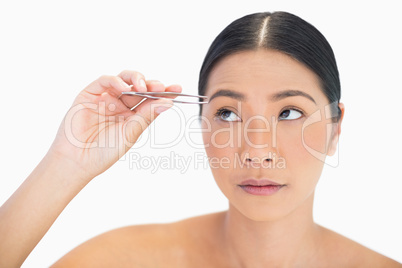 Thinking natural model using tweezers for her eyebrow