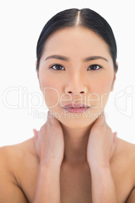 Serious pretty natural model posing with hands on her neck