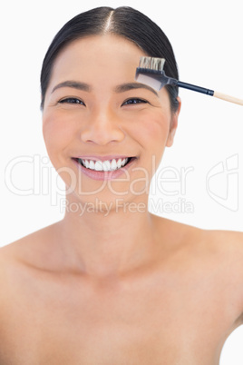 Cheerful pretty natural model using eyebrow brush