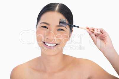 Smiling gorgeous natural model using eyebrow brush