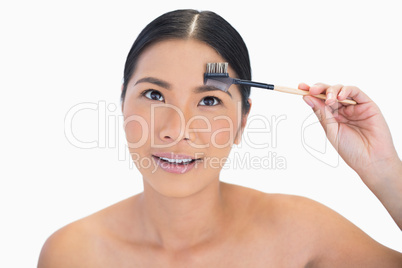 Pensive gorgeous natural model using eyebrow brush