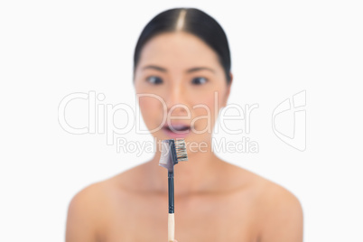 Curious natural model holding eyebrow brush