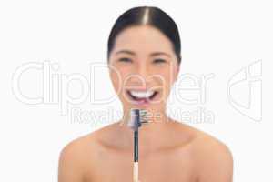 Cheerful natural model holding eyebrow brush in front of her