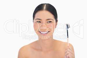 Smiling natural brunette holding eyebrow brush