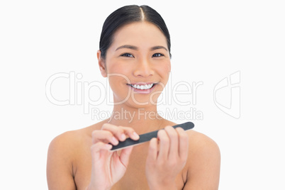 Cheerful natural brunette using nail file