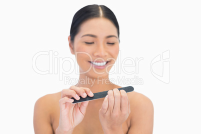 Happy natural brunette using nail file