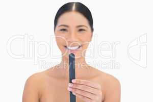 Smiling natural brunette holding nail file in front of her