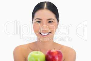 Smiling brunette holding red and green apples