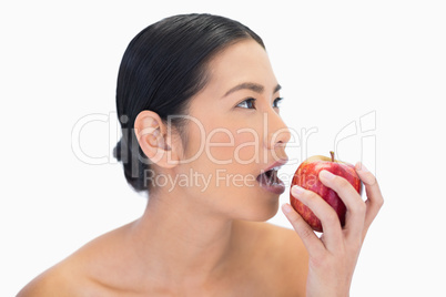 Thoughtful black haired model eating red apple