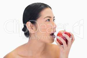 Thoughtful black haired model eating red apple