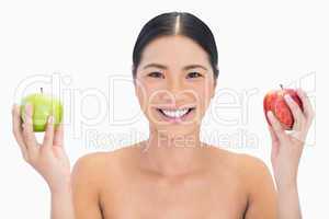 Cheerful black haired model holding apples in both hands
