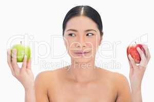 Black haired model holding apples in both hands looking at the g