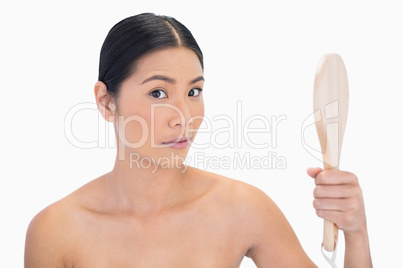 Surprised natural black haired model holding mirror