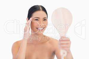 Natural dark haired model holding mirror touching her temple