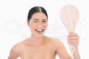 Laughing dark haired young model holding mirror