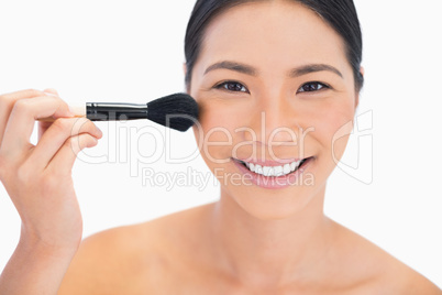 Dark haired young model applying powder on her face