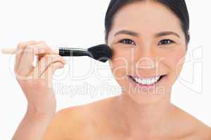 Cheerful dark haired model applying powder on her face