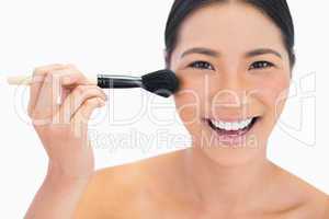 Smiling dark haired model applying powder on her face
