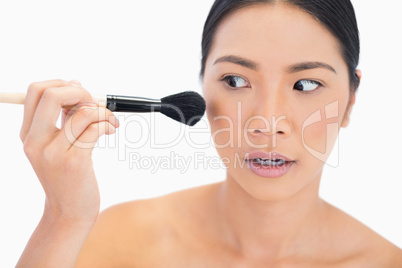 Nervous dark haired model applying powder on her face