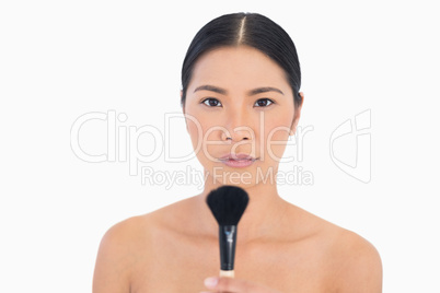 Serious dark haired woman holding powder brush