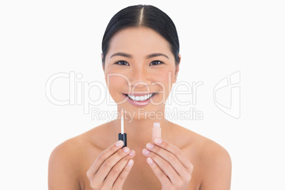 Smiling beautiful model holding lip gloss