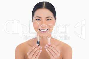 Smiling beautiful model holding lip gloss