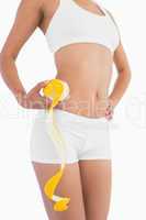 Female slender body in sport underwear holding orange