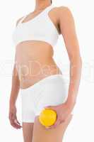 Firm female body with white sport underwear holding orange