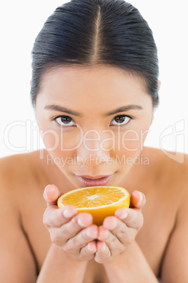 Content pretty woman holding orange in her hands