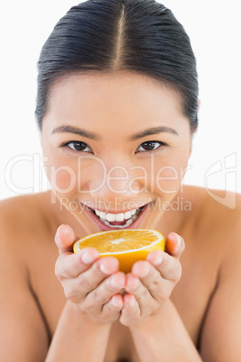 Cheerful pretty woman holding orange slice in her hands