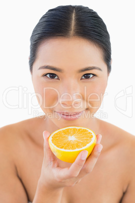 Peaceful pretty woman holding orange slice in her hand