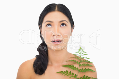 Pretty dark haired woman with fern looking up