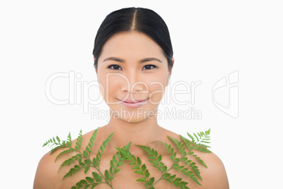 Sensual dark haired model posing with fern
