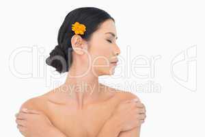 Pensive model with orange flower in hair touching her shoulders