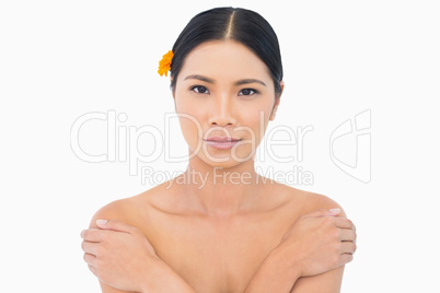 Sensual model with orange flower in hair touching her shoulders