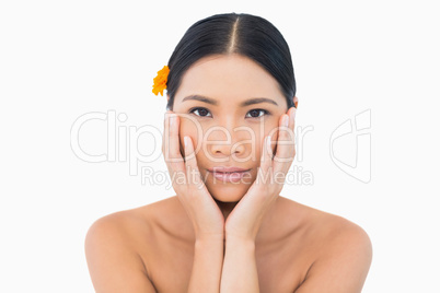 Sensual model with orange flower in hair touching her face