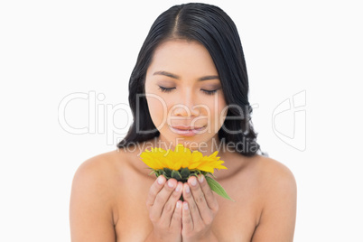 Natural black haired model smelling sunflower